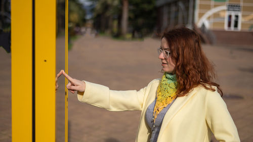 Side view of young woman standing against trees