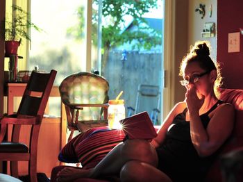 Woman using digital tablet while sitting on sofa at home