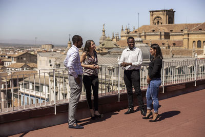 Smiling male and female entrepreneurs discussing on rooftop of office building during break