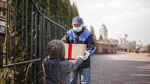 Rear view of girl holding parcel outdoors