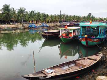 Boats moored at harbor against sky