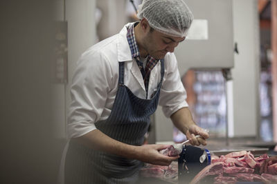 Butcher packing raw meat in butchery