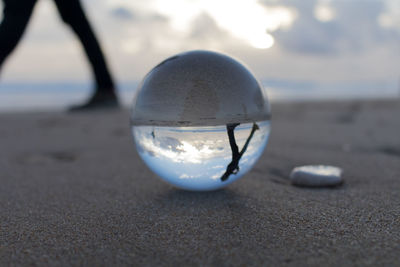 Person reflecting on crystal ball at beach