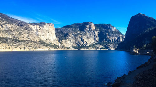 Scenic view of sea and mountains against clear blue sky