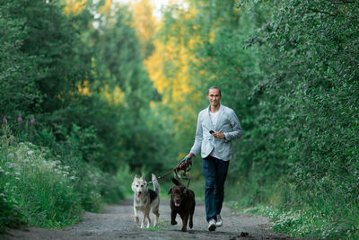 Full length of man with dogs walking on footpath 