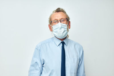 Portrait of senior man wearing mask against white background