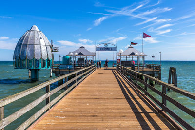 Pier over sea against blue sky