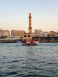 Buildings by sea against clear sky