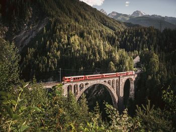 Train on bridge against mountains