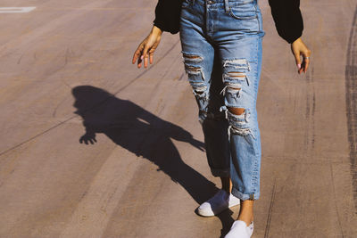 Low section of woman wearing jeans standing on road