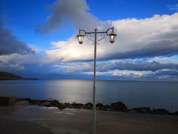 Street light by sea against sky