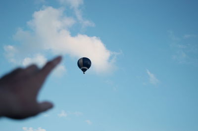 Cropped image of hand pointing at hot air balloon