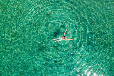 Aerial view of a girl floating in the turquoise sea on the cres island, adriatic sea, croatia