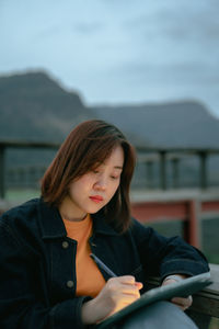 Asian woman use tablet for stock and cryptocurrency trading from outdoor of coffee shop