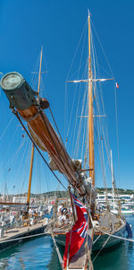 Sailboat moored at harbor against clear blue sky