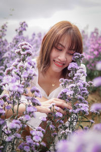 Portrait of young woman standing amidst purple flowers