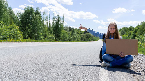 Portrait of woman using mobile phone while sitting on road