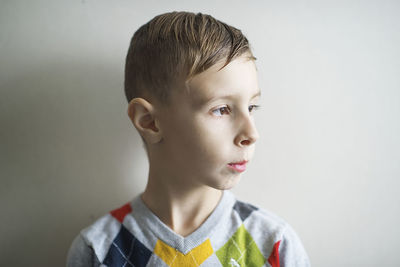 Close-up of boy looking away against gray background