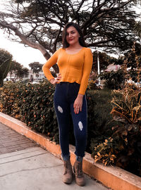 Portrait of young woman standing against trees