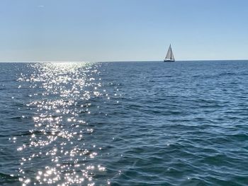Sailboat sailing in sea against clear sky