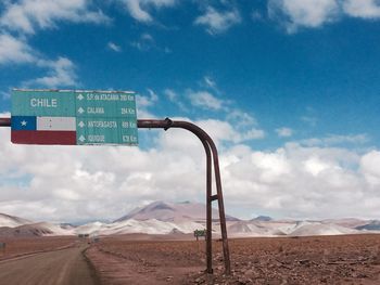 Road sign in desert against sky