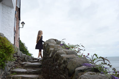 People sitting on rock by sea against sky