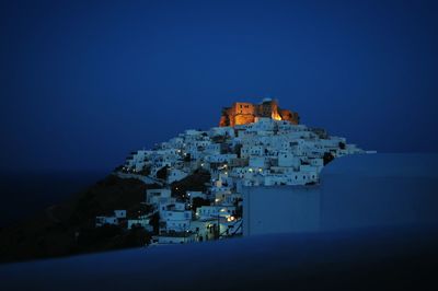 Castle and buildings against blue sky at night