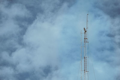 Low angle view of communications tower against cloudy sky