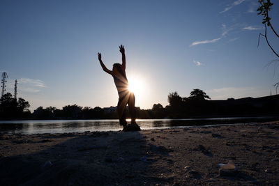 Rear view of woman jumping at beach against sky