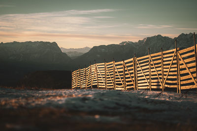 Wooden posts on mountain against sky during sunset