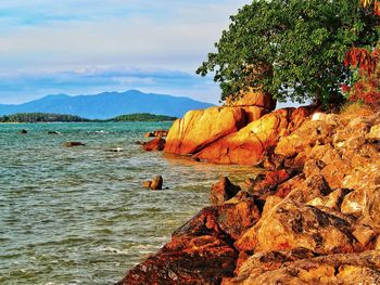 Scenic view of rocks by sea against sky