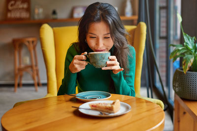 Young woman using mobile phone while sitting on table