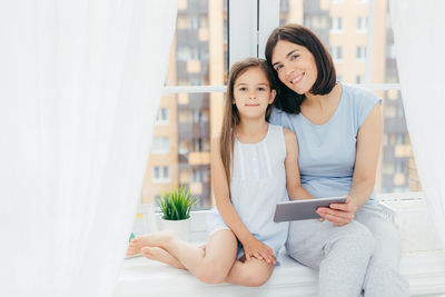 Mother and daughter while sitting on mobile phone