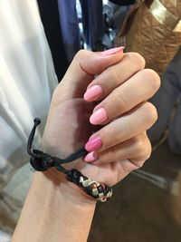 Cropped hand of woman with painted nails wearing bracelet at home