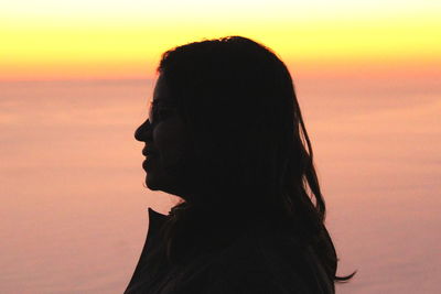 Close-up portrait of silhouette woman against sea during sunset