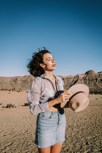 FULL LENGTH OF WOMAN STANDING ON SAND DUNE