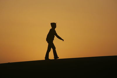 Silhouette of person walking at sunset