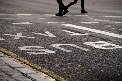 Low section of person with text on road