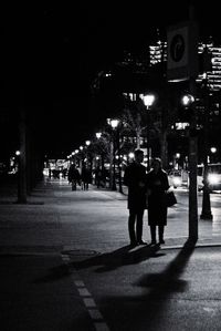 People on illuminated street in city at night