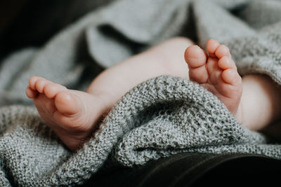 Low section of baby lying on bed