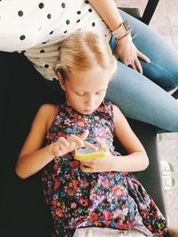 High angle view of girl using smart phone while resting at home with mother