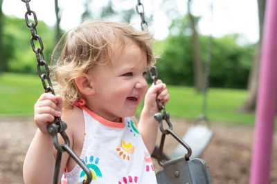 Cute girl looking away while sitting on swing 