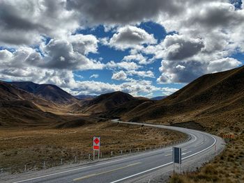 Road by mountains against sky