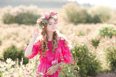 Teenager girl holding flower bouquet standing at field