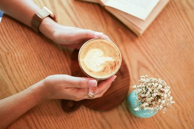 Midsection of woman holding coffee cup on table