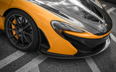 Close-up of yellow car parked against orange background