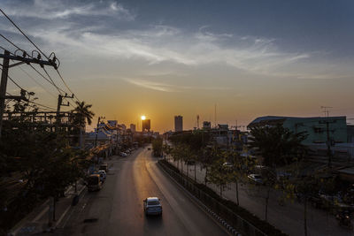 Cars on street in city against sky during sunset