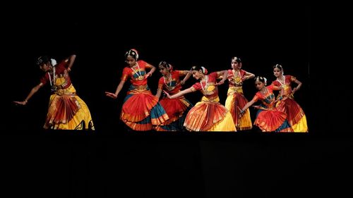 Group of people dancing against black background