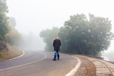 Full length of man standing on road against trees