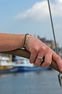 Close-up of man holding hands against sky